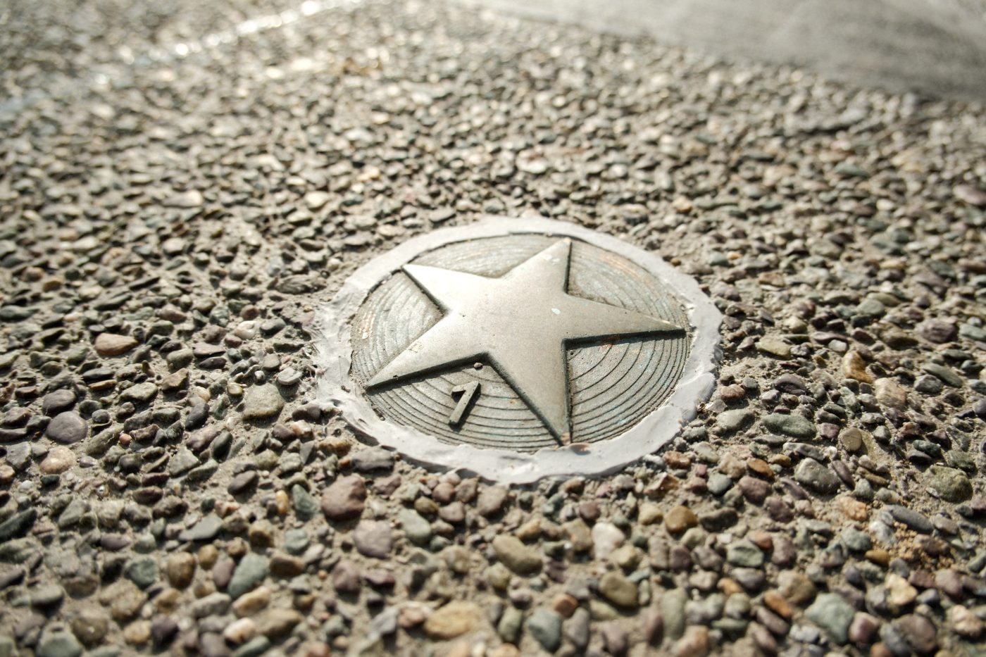 A bronze star set into the gravel surface, numbered 1